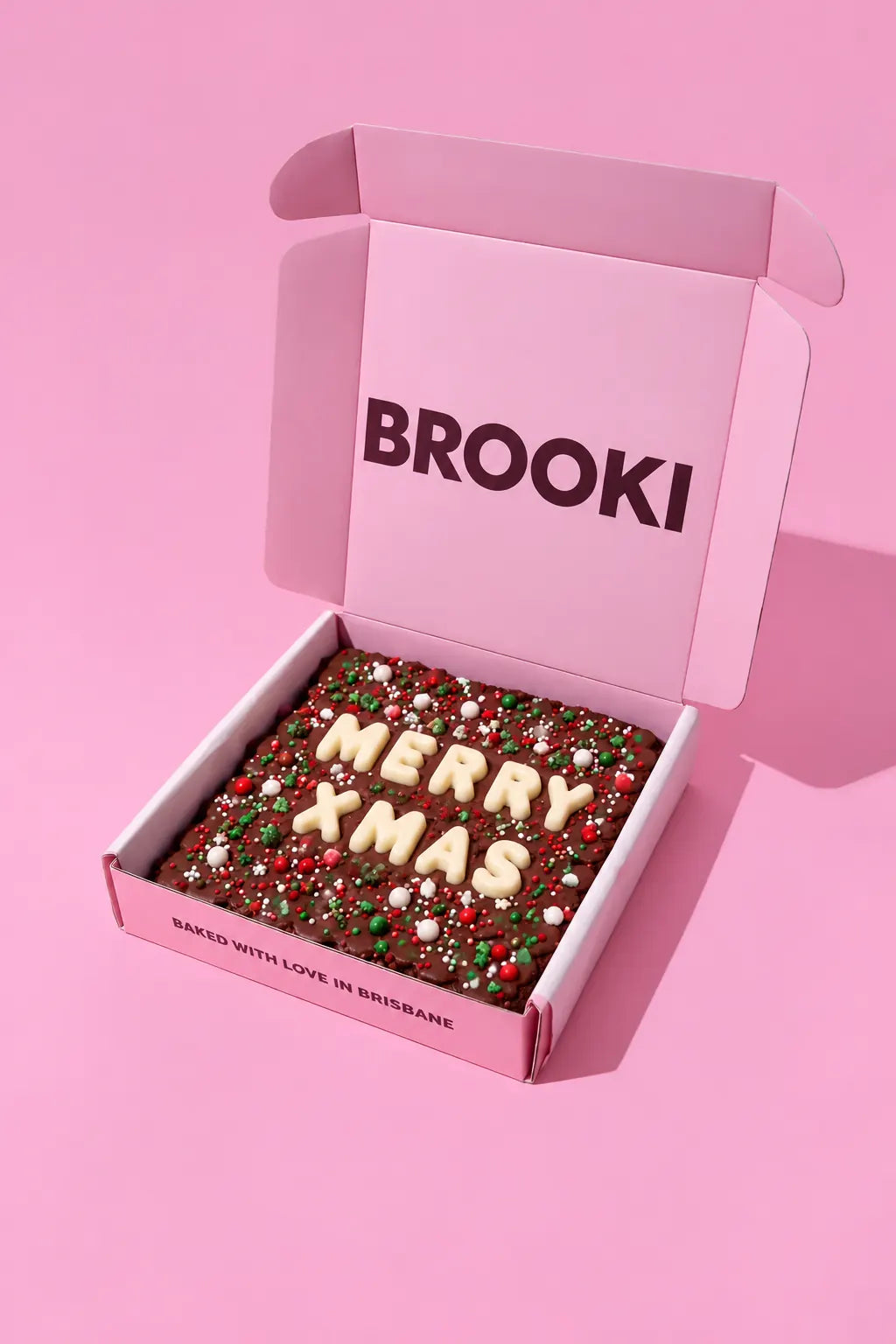Brooki Christmas Brownie with white chocolate MERRY XMAS letters and red, green and white sprinkles in a pink BROOKI gift box